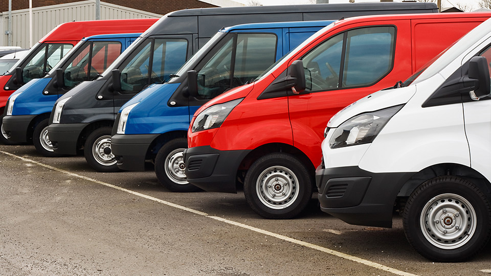 Una fila di furgoni di modelli diversi parcheggiati uno accanto all'altro