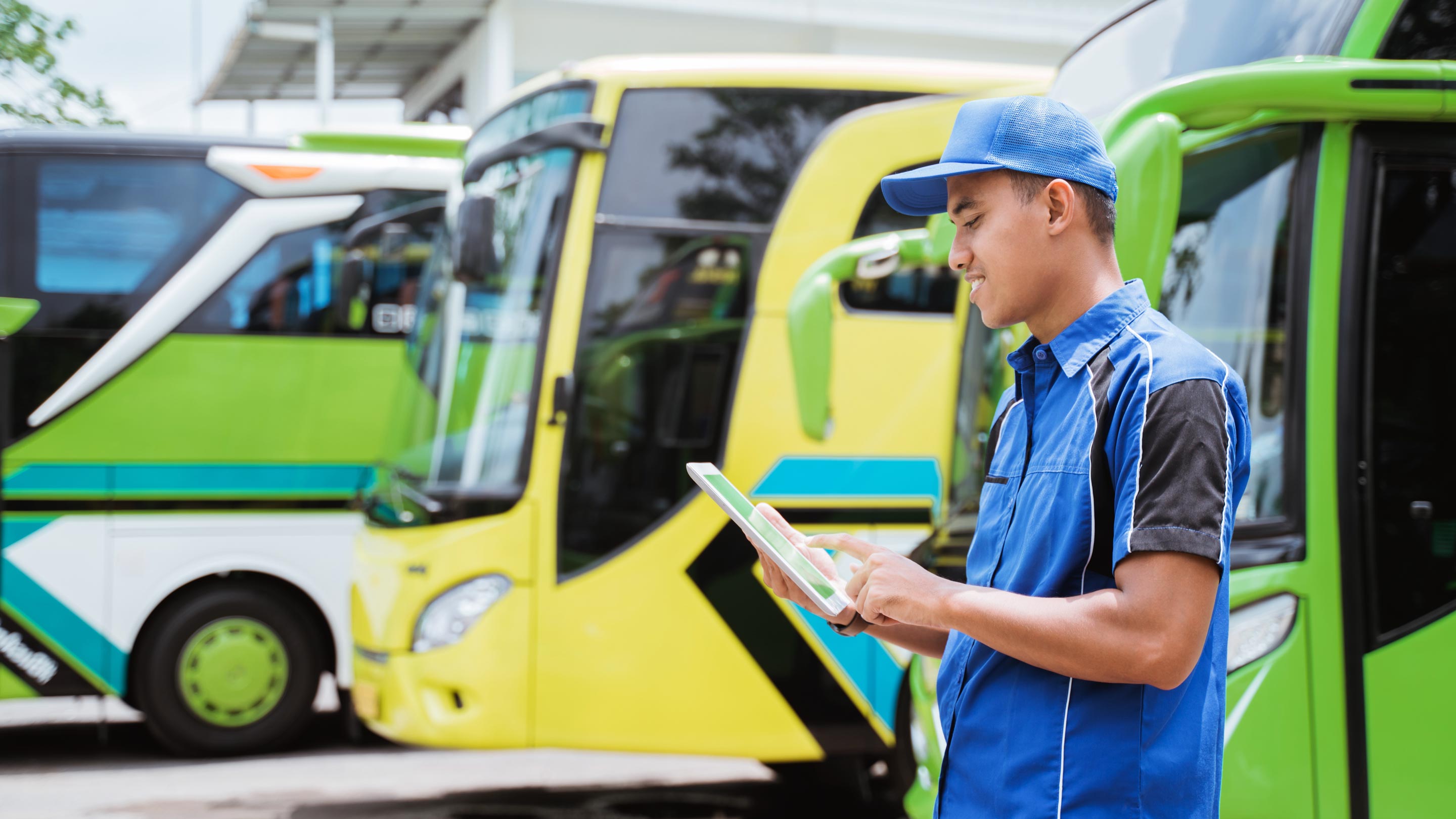 Uomo che usa un tablet con autobus parcheggiati sullo sfondo