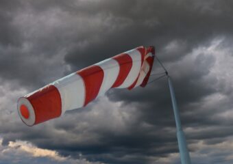 Windsock, orange and white striped, indicating strength of wind strength before an approaching storm, which is appearing in the background.