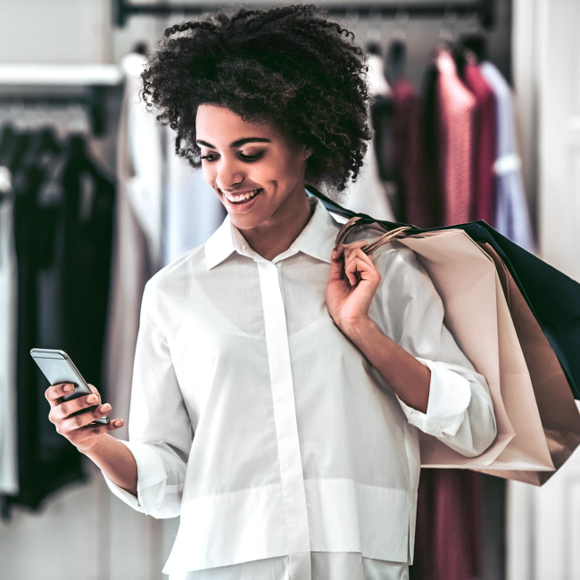 Frau mit Einkaufstüten und Handy in der Hand