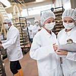 Women working at a food factory and looking at checklist on a clipboard.