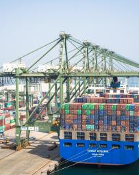 Container ship coming into a port with cranes overhead