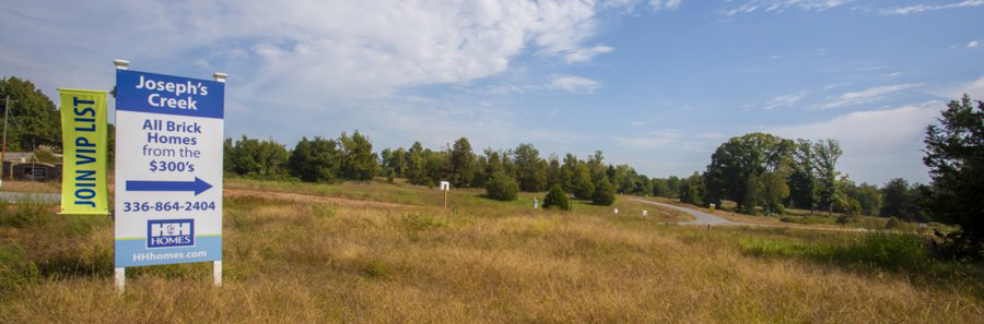 A strip of land with a for sale sign in front of it