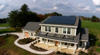 A newly built two-story home with an attached garage has solar panels on the roof.