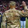 A view from behind as a military officer raises his right hand to administer the oath of enlistment to recruits.