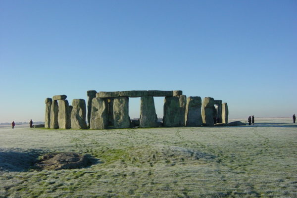 Stonehenge against a clear blue sky with the Slaughter stone in the foreground