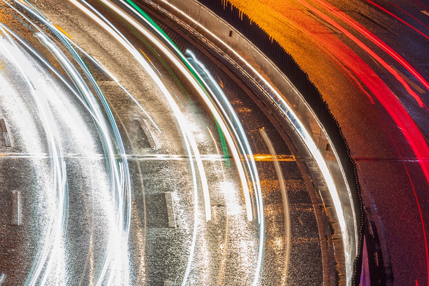 Curve of a multi-lane road at night, the lights of the cars form luminous lines, the cars are not recognizable 