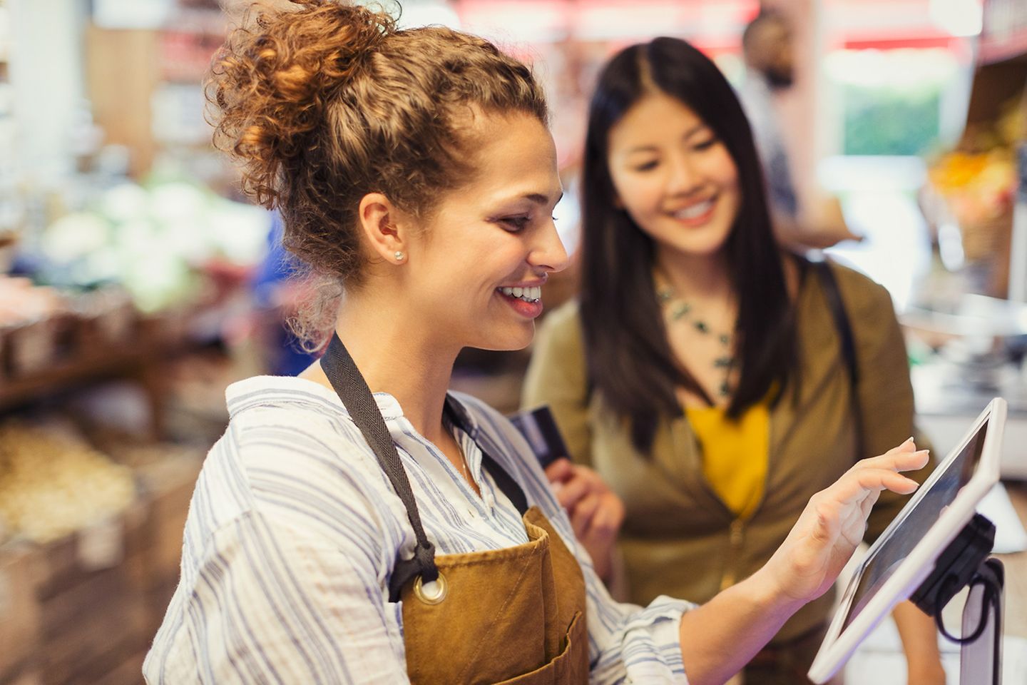 Cashier helps customer at a touch screen of a digital checkout in a supermarket