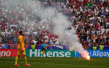 A Flare thrown from the stands burns on the pitch during a Group C match between Slovenia and Serbia