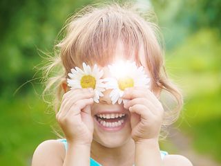 Girl holding flowers to her eyes.