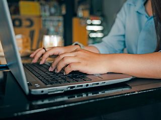 Hands typing on the keyboard of a laptop.