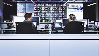 A male and female colleague, sitting at their respective work desks.