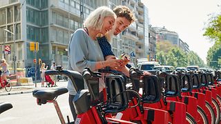 Two friends unlocking some public bikes.