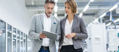 Workmates walking and discussing a subject while looking at a tablet