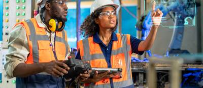 Engineer using tablet to check the robot system while her teamwork checks the security of the robot.