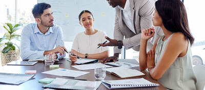 Four people attending a meeting in an office with lots of bright windows