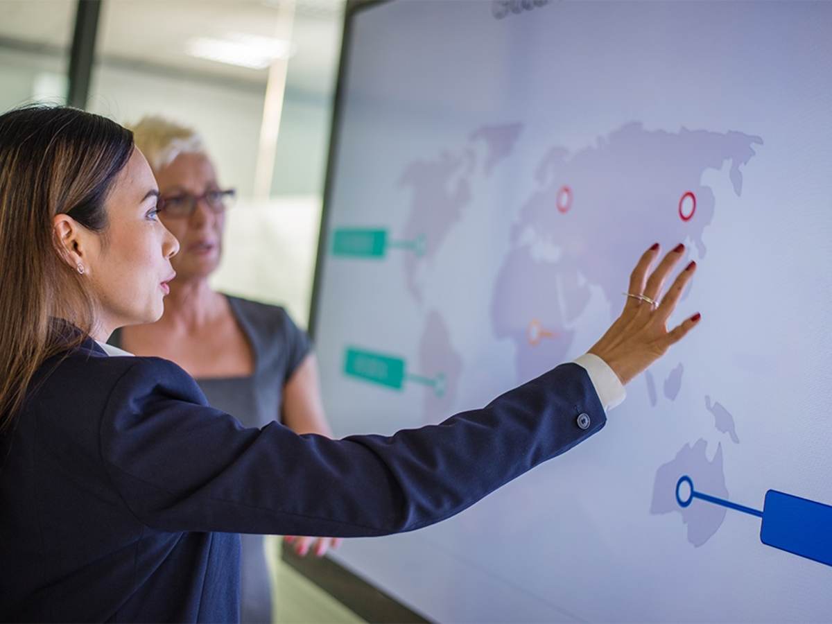 Two people gesturing at a screen in a business presentation