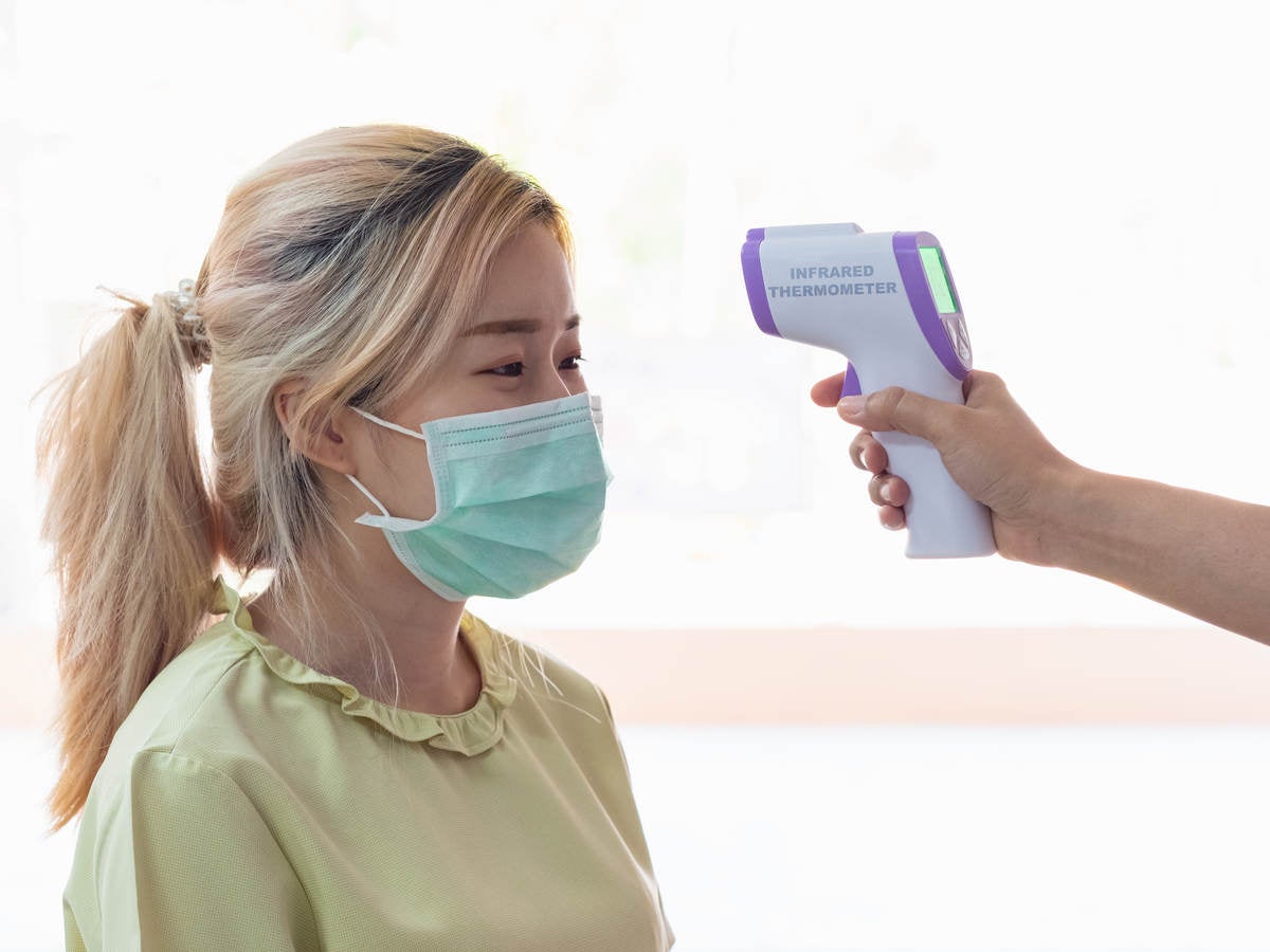 Lady wearing a mask getting temp scanned