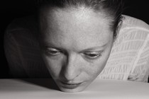 Black-and-white image of a woman placing her chin on the table