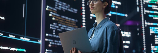 imagen sobre la IA y su impacto en el empleo con una chica delante de unas pantallas sosteniendo un portátil
