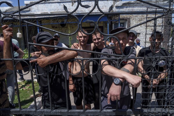 Prisoners stand behind the fence in the barrack's yard in a prison, in the Dnipropetrovsk region, Ukraine, Friday, June 21, 2024. Ukraine is expanding its military recruiting to cope with battlefield shortages more than two years into fighting Russia’s full-scale invasion. (AP Photo/Evgeniy Maloletka)