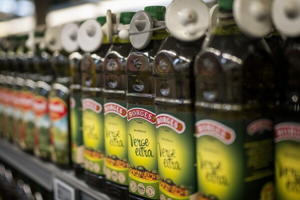Bottles of virgin olive oil, sealed with an anti-theft system, are photographed on a shelf in a shop in Barcelona, Spain, Tuesday, June 25, 2024. Spain will temporarily eliminate sales tax on olive oil to help consumers cope with skyrocketing prices, the government said Tuesday. (AP Photo/Emilio Morenatti)