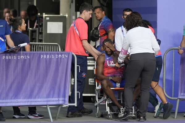 Noah Lyles, of the United States, is helped off the track after the men's 200-meter final at the 2024 Summer Olympics, Thursday, Aug. 8, 2024, in Saint-Denis, France. (AP Photo/Matthias Schrader)