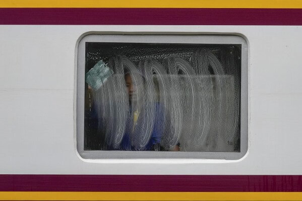 A worker cleans a window of a train at Hua Lampong Railway Station in Bangkok, Thailand, Thursday, June 27, 2024. (AP Photo/Sakchai Lalit)