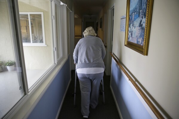 FILE - A woman walks to her room at a senior care home in Calistoga, Calif., on Dec. 5, 2019. (AP Photo/Eric Risberg, File)