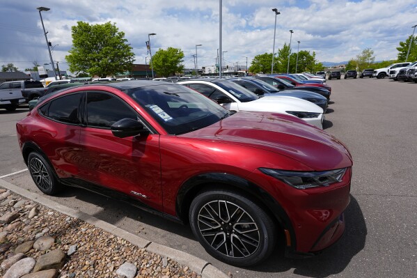 FILE - A line of unsold 2024 Mustang Mach-E electric utility vehicles sit at a Ford dealership May 19, 2024, in Denver. On Tuesday, July 2, 2024, automakers will report second-quarter U.S. sales and they're expected to be flat compared with a year ago. (AP Photo/David Zalubowski, File)