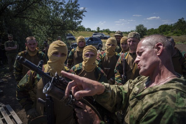 A Ukrainian military instructor of Arey Battalion demonstrates to convict prisoners who have joined the Ukrainian army how to use a grenade luncher on a rifle during training at the polygon, in the Dnipropetrovsk region, Ukraine, Saturday, June 22, 2024. Ukraine is expanding its military recruiting to cope with battlefield shortages more than two years into fighting Russia’s full-scale invasion. (AP Photo/Evgeniy Maloletka)
