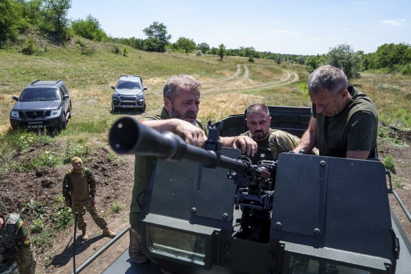 A Ukrainian servicemen aka "Kherson",center, deputy commander of Arey Battalion prepares a machine gun during training at the polygon, in the Dnipropetrovsk region, Ukraine, Saturday, June 22, 2024. Ukraine is expanding its military recruiting to cope with battlefield shortages more than two years into fighting Russia’s full-scale invasion. (AP Photo/Evgeniy Maloletka)