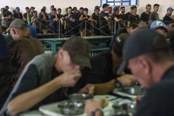 Prisoners wait in line for lunch in a prison, in the Dnipropetrovsk region, Ukraine, Friday, June 21, 2024. Ukraine is expanding its military recruiting to cope with battlefield shortages more than two years into fighting Russia’s full-scale invasion. (AP Photo/Evgeniy Maloletka)