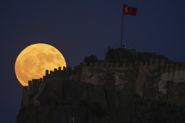 A full moon rises behind old Karahisar castle in Afyonkarahisar, central Turkey, Friday, June 21, 2024. (AP Photo/Emrah Gurel)