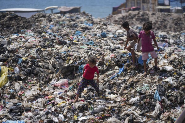 Palestinian kids sort through trash at a landfill in Nuseirat refugee camp, Gaza Strip, Thursday, June 20, 2024.  (AP Photo/Abdel Kareem Hana)