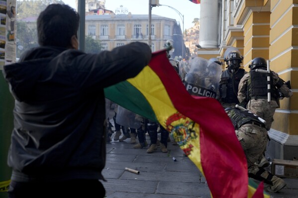 A supporter of President Luis Arce waves a Bolivian flag as soldiers flee from Plaza Murillo, after a failed coup attempt, in La Paz, Bolivia, Wednesday, June 26, 2024. (AP Photo/Juan Karita)