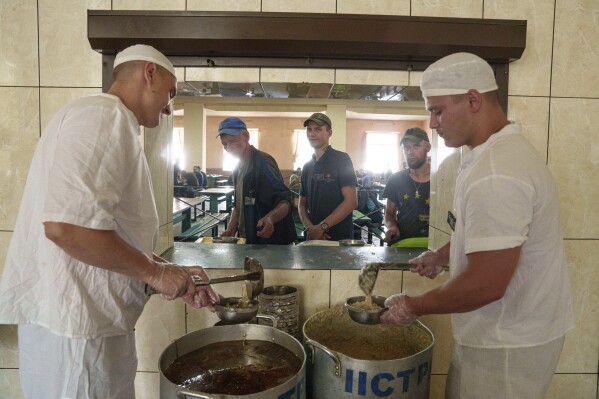 Prisoner Ernest Volvach, right, serves porridge, during lunch in a prison, in the Dnipropetrovsk region, Ukraine, Friday, June 21, 2024. Ukraine is expanding its military recruiting to cope with battlefield shortages more than two years into fighting Russia’s full-scale invasion. (AP Photo/Evgeniy Maloletka)