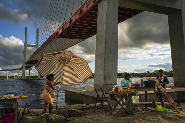 Vendors set up food stands under a bridge that is part of a federal highway project that extends over the Nanay River, in Iquitos, Peru, Monday, May 27, 2024. (AP Photo/Rodrigo Abd)