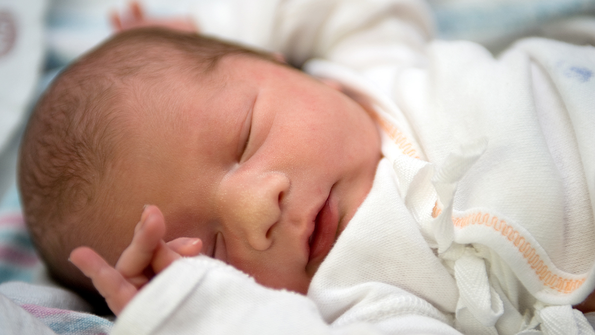 Close-up portrait of a newborn baby dressed in white