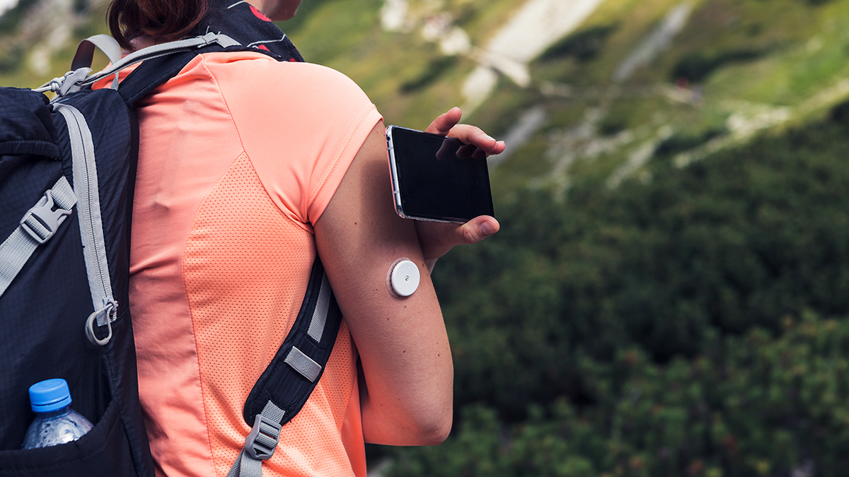 Person hiking and using continuous glucose monitor