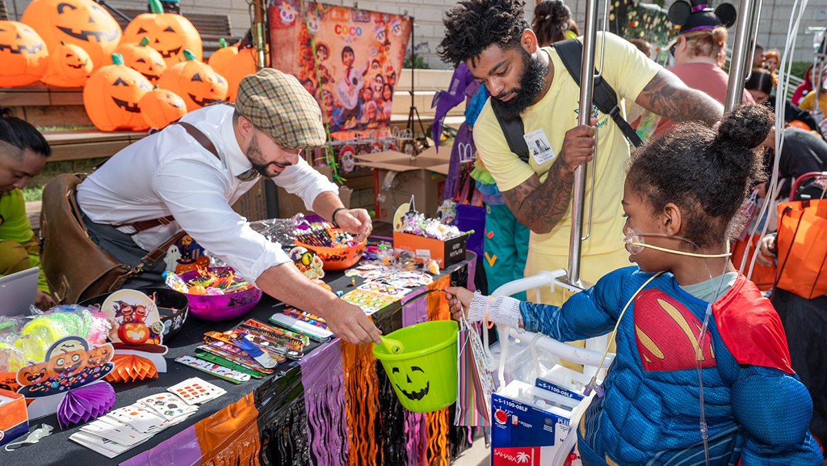 Girl holding green Halloween pail to get candy