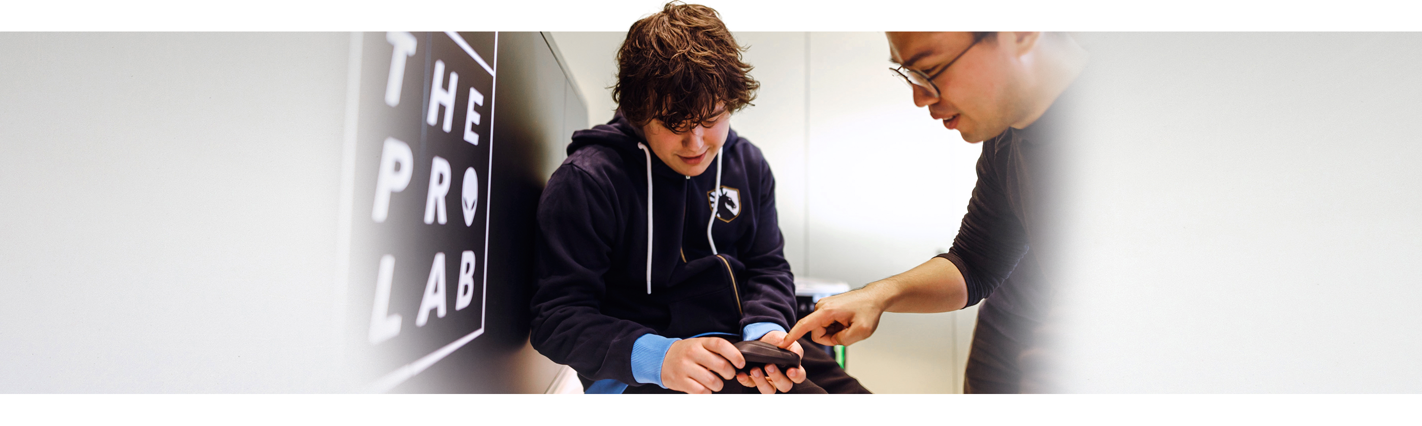 Boy holding a Dell Alienware Pro Wireless Gaming Mouse with a man next to him pointing at the product. 