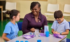 Maggie Aderin-Pocock smiles as she sits between two pupils at a table