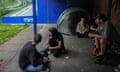 People living in a tent sit and chat next to a government "Levelling Up' poster in Boston, England