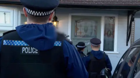 Police officers in uniform standing in front of a door