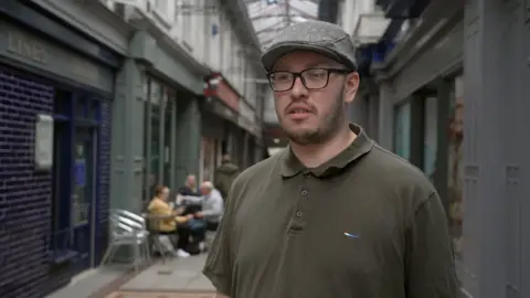 Man wearing flat cap and polo shirt standing in arcade