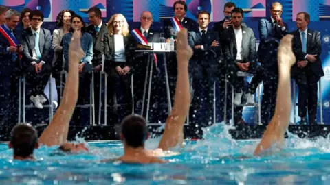 Reuters President Macron and other officials watch synchronised swimmers in a pool