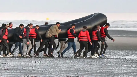 Migrants in France carry a dingy in an attempt to cross the Channel