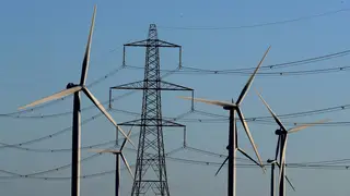 A wind farm in front of a pylon