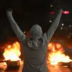 A protestor raises his arms in front of tires on fire in Caracas, Venezuela, the day after the presidential election